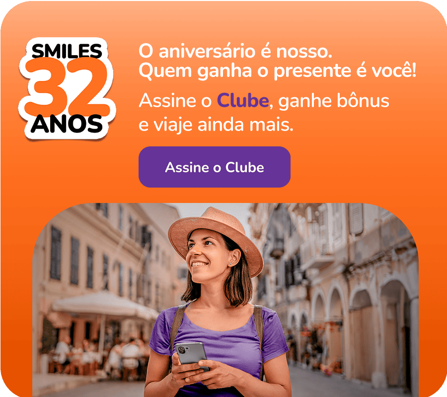 Mulher de blusa roxa com chapéu, com celular na mão, olhando para o horizonte.