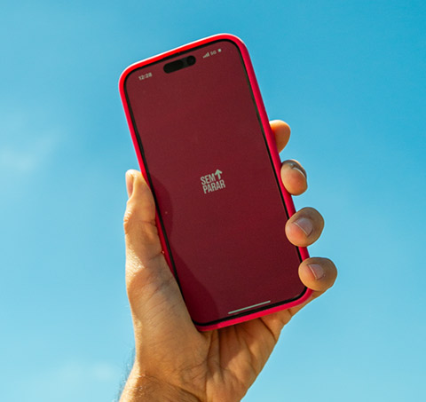 Mão segurando um celular com o aplicativo Sem Parar aberto.