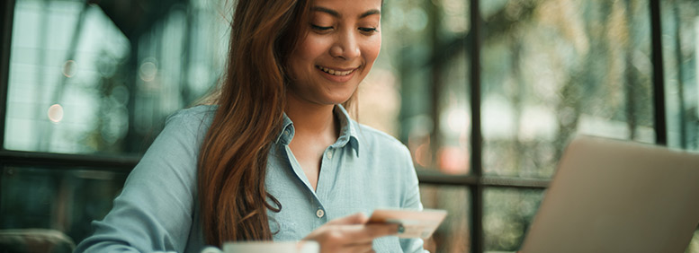 Mão segurando um cartão de crédito diante do celular